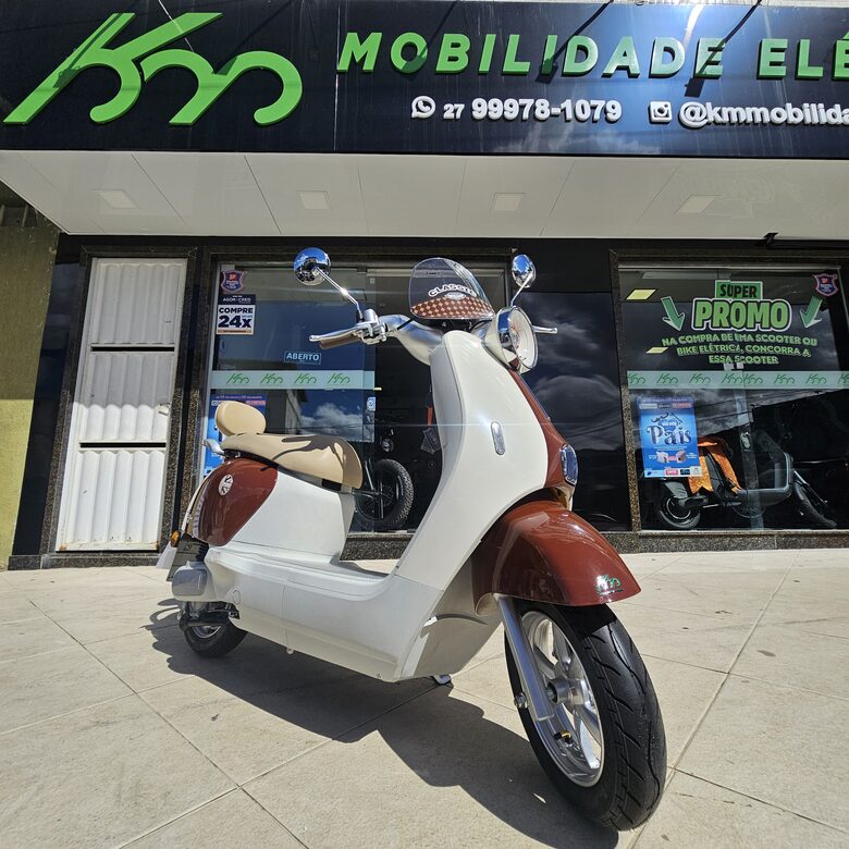 Scooter elétrica retrô branca e vinho em frente à loja da KM