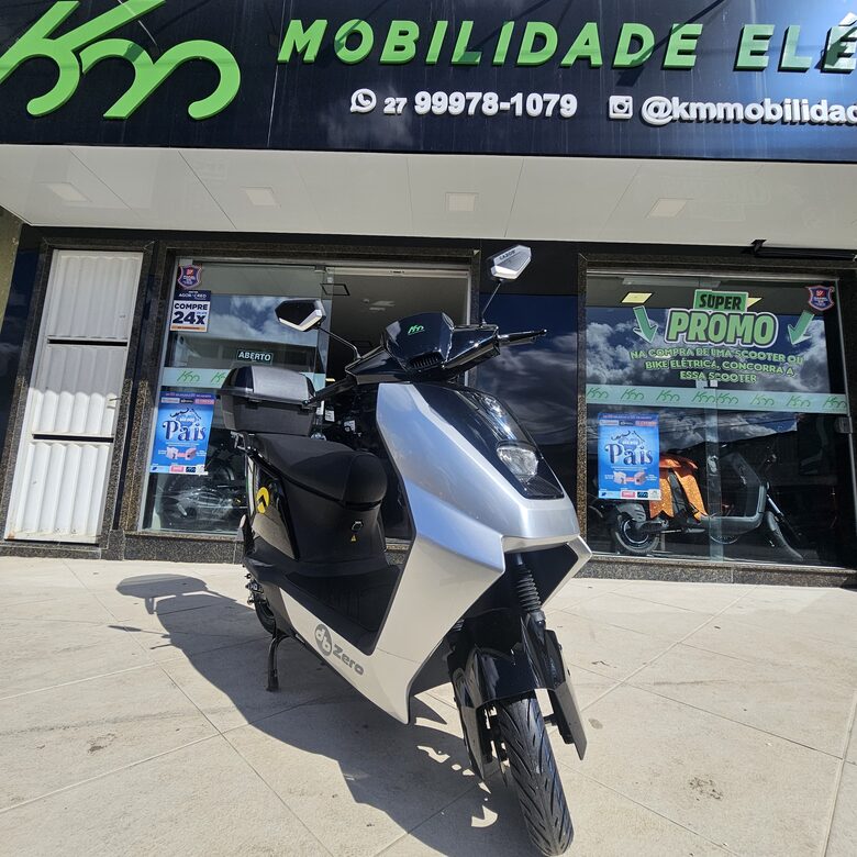 Scooter elétrica esportiva prata e preta em frente à loja da KM